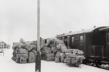 Paket i en stor hög på perrongen bredvid ett tåg i början av 1900-talet.