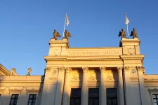 Universitetshusets fasad i solljus mot blå himmel. Foto.