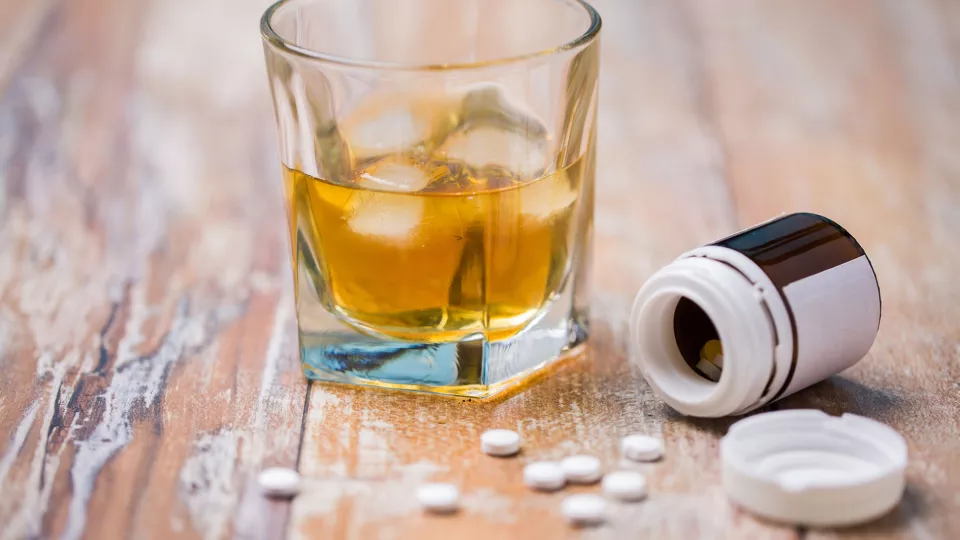 bild på ett glas med alkohol och en burk med tabletter