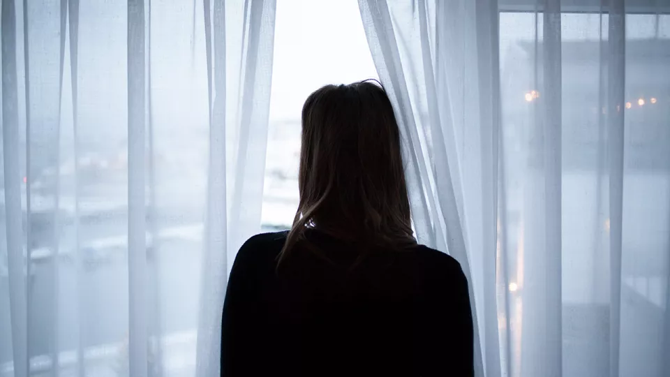Ung kvinna bakifrån vid fönster