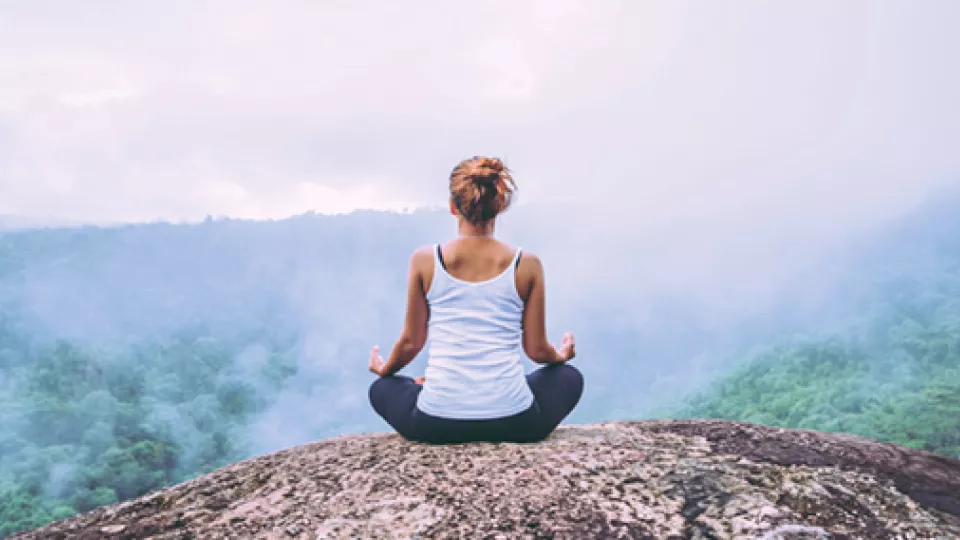 Kvinna sitter på ett berg och gör yoga