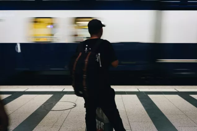 Siluett av man som står framför ett tåg. Foto.