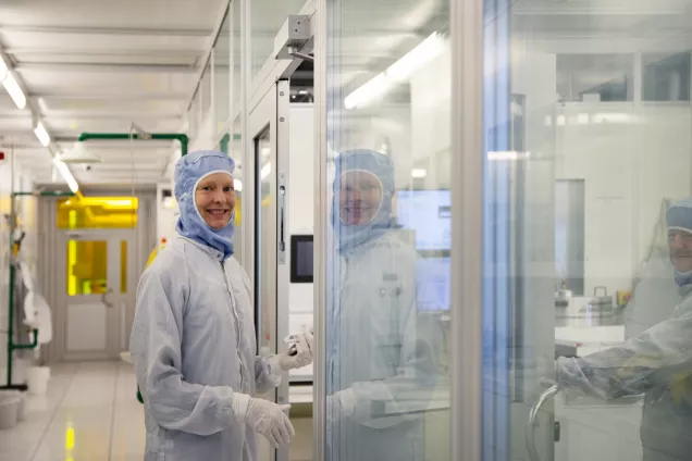 Photo of a woman in the clean room, wearing protective clothes.