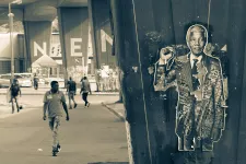 Gatukonst föreställande Nelson Mandela. I bakgrunden personer som går på en gata i Sydafrika. Svartvitt foto.