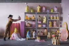 Hanna Hansdotter placerar sina stora färgglada vaser och skulpturer i ett hyllsystem.