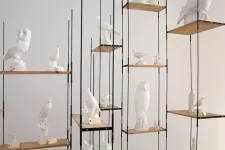 Fågelskulpturer i vit stearin i ett hyllsystem. 