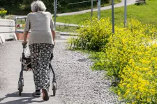 Äldre kvinna som går med hjälp av rullator utomhus,