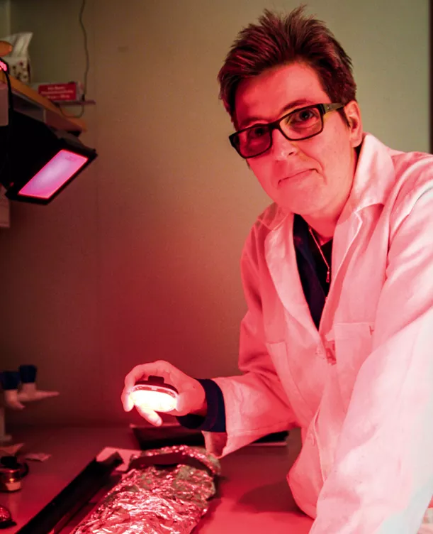 Kvinna i vit rock i laboratorium med rött ljus