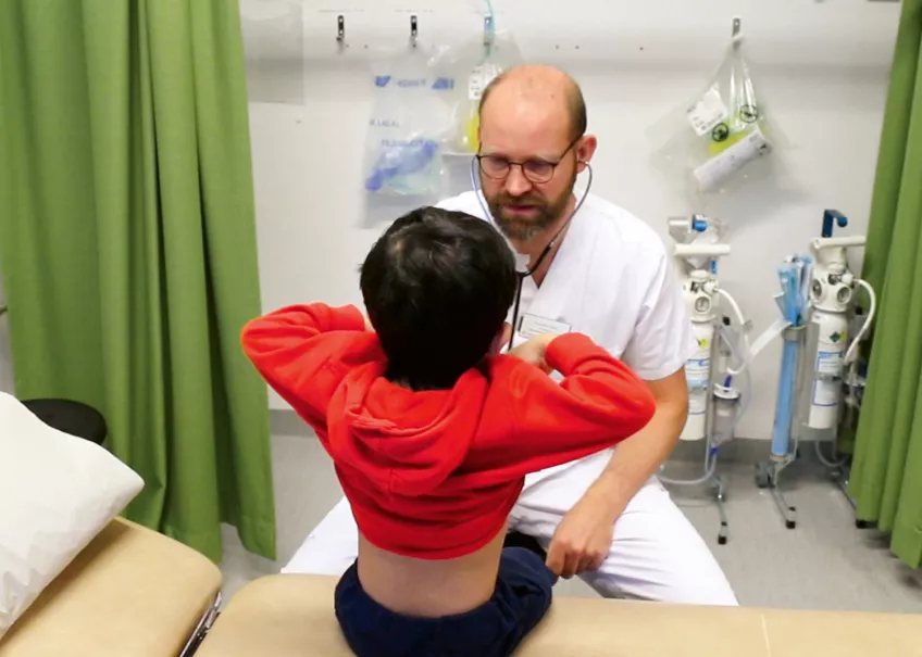 Läkare undersöker ett barn (som man ser ryggen av)